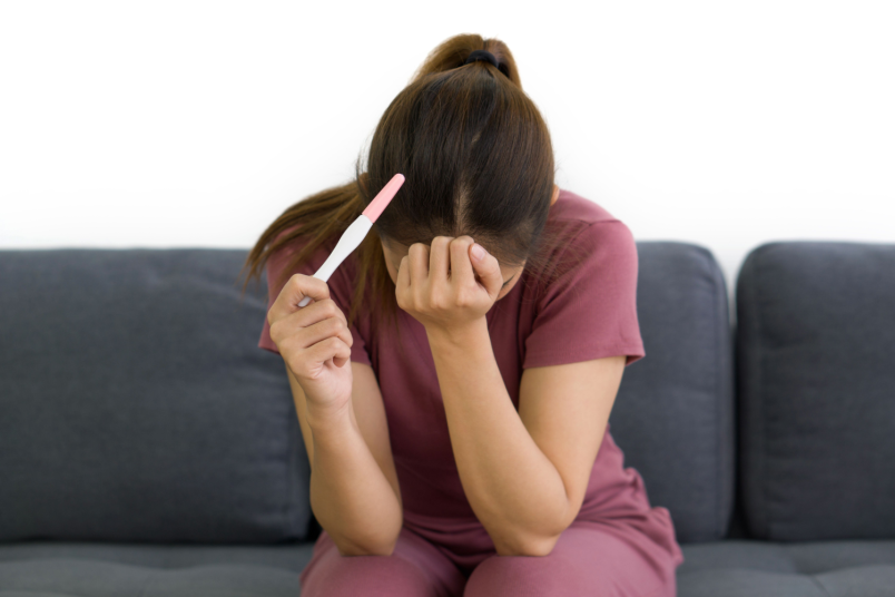 Depressed Woman Holding Pregnancy Test Kit - NU Fertility